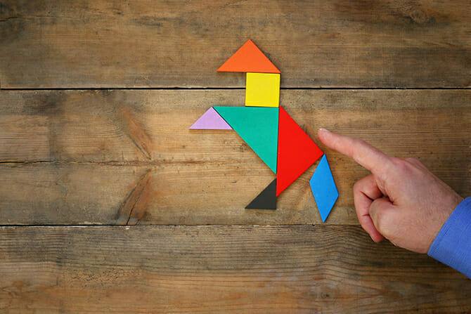 Erlebnispädagogik Ausbildung - Mann zeigt mit Hand auf Tangram Puzzle Pferd