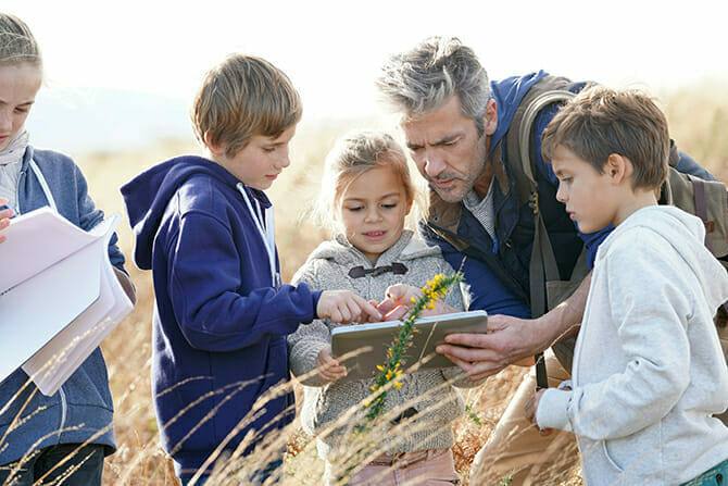 Erlebnispädagogik Ausbildung - Lehrer studiert Pflanzen und Blumen mit Kindern