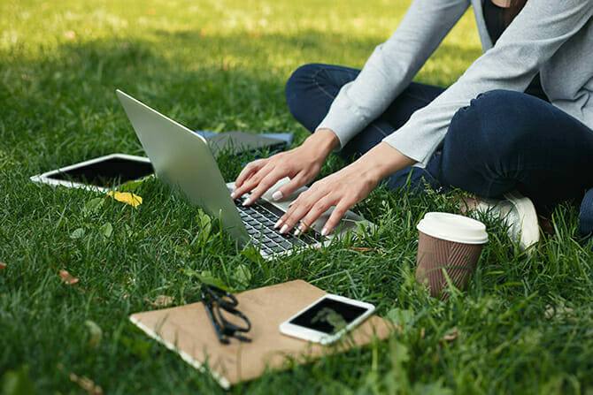 Hundetrainer Ausbildung Inhalt - Frau lernt outdoor am Laptop