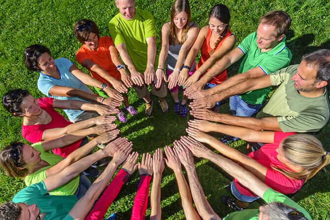 Erlebnispädagogik Ausbildung - Gurppe Erwachsene und Kindern bilden Kreis mit Händen