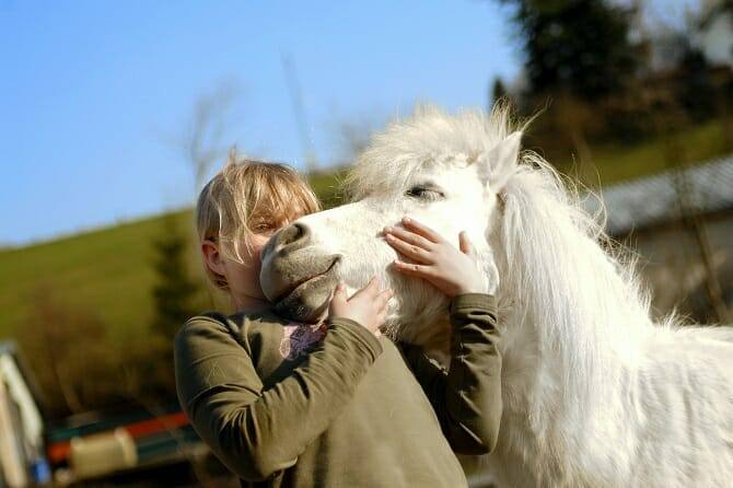 Tiergestützte Arbeit Ausbildung - junges Mädchen verliebt in ihr weißes Pony