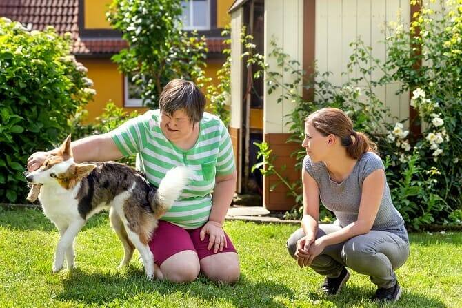 Assistenzhundetrainer Ausbildung - Geistig behinderte Frau mit Betreuerin und Hund im Garten
