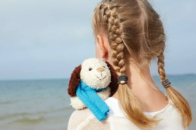 Psychologischer Coach Mensch Tier Beziehung Ausbildung - blondes Mädchen mit Zöpfen am Strand mit Plüschhund