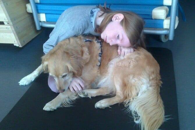 Tiergestützte Arbeit Ausbildung - junge Frau umarmt liegenden Golden Retriever